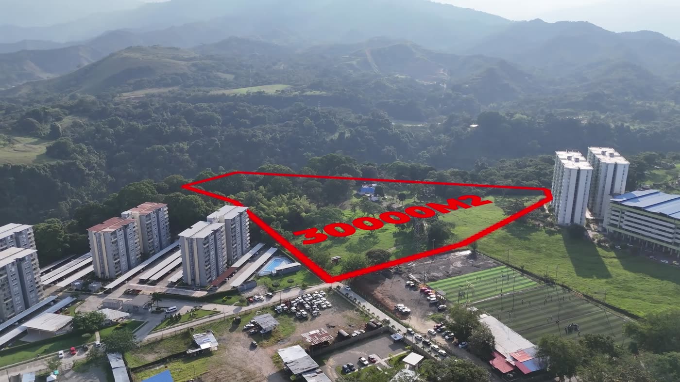 Toma aérea del lote con el polígono del lindero trazado en rojo y los conjuntos de vivienda vecinos.